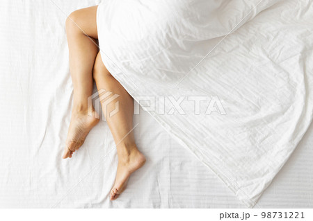 Slim, perfect and beautiful womans legs on white bed Slim, perfect and beautiful womans legs on white bed 98731221