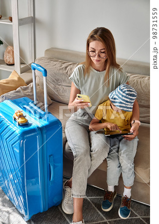 Family mother and child buy vacation or travel tickets using mobile phone and tablet at home 98731559