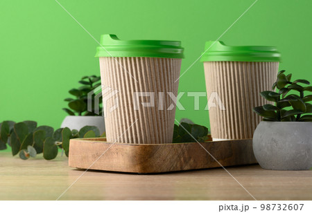 Paper brown cups with a plastic green lid for coffee and tea on a green background 98732607
