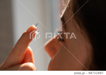 Close-up portrait caucasian woman putting on a contact lens.  98732897