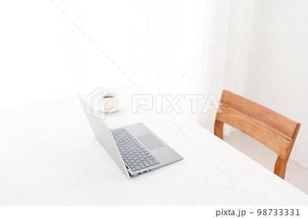 白い机の上にあるノートパソコンとコーヒーカップ（キーボードピント） 98733331
