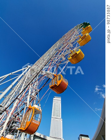 青い空オレンジ色の大きな観覧車と高層ビル 青い空オレンジ色の大きな観覧車と高層ビル 98733887