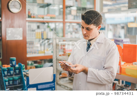 Pharmacist checking Checks Inventory of Medicine, Drugs, Vitamins and prescription medication checks in modern pharmacy. Pharmacist checking Checks Inventory of Medicine, Drugs, Vitamins and prescription medication checks in modern pharmacy. 98734431