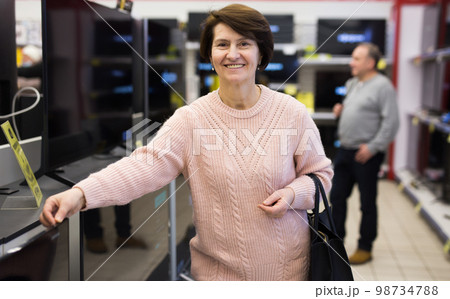 Portrait of a smiling woman standing in the department with televisions 98734788