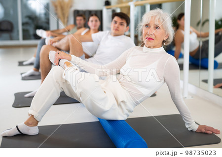 Women and men doing stretching workout during group training in yoga class Women and men doing stretching workout during group training in yoga class 98735023