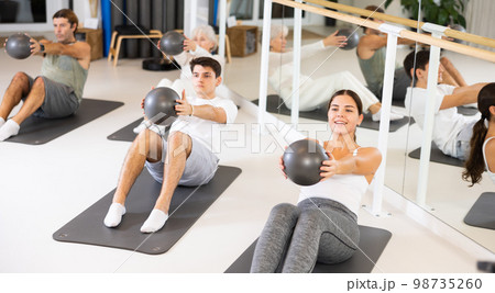 Young woman practicing pilates with ball in gym room 98735260