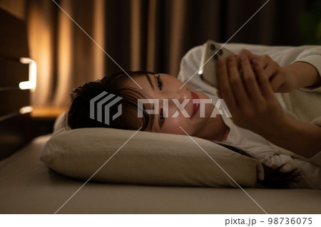 ベッド・寝室でスマホを操作する女性 98736075