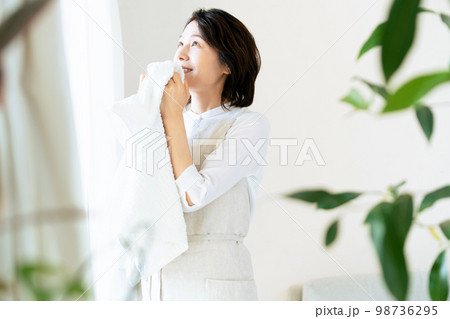窓辺で洗ったタオルの匂いを確認する女性 窓辺で洗ったタオルの匂いを確認する女性 98736295