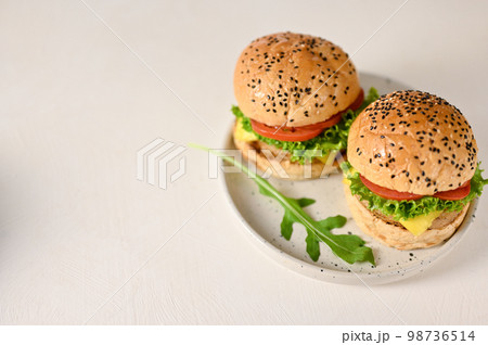 Top view of tasty beef burgers on minimal white ceramic plate with copy space on white tabletop Top view of tasty beef burgers on minimal white ceramic plate with copy space on white tabletop 98736514
