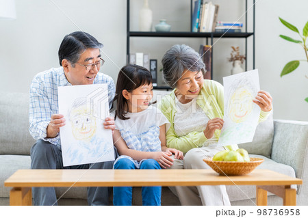 リビングで団らんする祖父母と孫娘 リビングで団らんする祖父母と孫娘 98736958