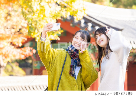 スマホで記念写真を撮る若い女性 98737599