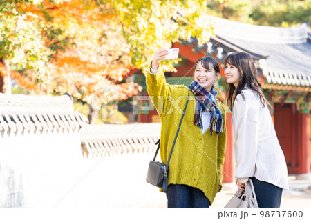 スマホで記念写真を撮る若い女性 98737600