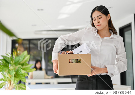 Sad Asian female office worker carrying her belonging, quitting a job, being fired from her boss. 98739644