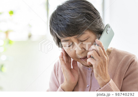 スマートフォンで通話する不安な表情の高齢の女性 98740292