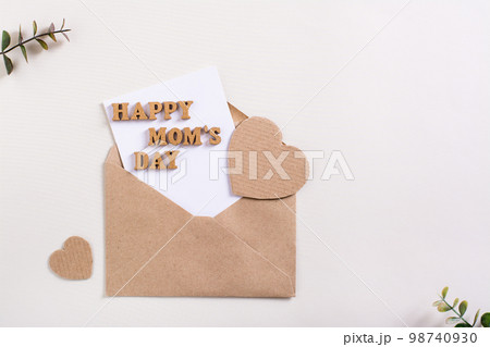 Happy mother's day. Envelope with a sheet, letters and hearts on a light background. 98740930