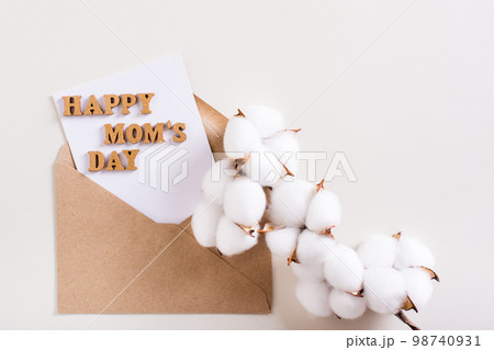 Happy mother's day. Envelope with a sheet, letters and a branch of cotton on a light background. 98740931