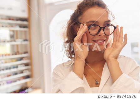 Optical Shop. Woman Trying On Eyeglasses Near Showcase Optical Shop. Woman Trying On Eyeglasses Near Showcase 98741876