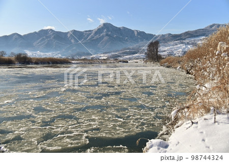 蓮葉氷漂う千曲川と冠着山の冬景色 98744324