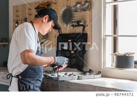 家のガレージで工具を使う男性（DIY・クラフト・日曜大工・ワークショップ・体験教室・リフォーム） 98744372