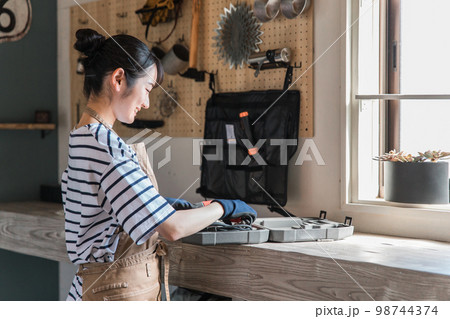 家のガレージで工具を使う女性（DIY・クラフト・日曜大工・ワークショップ・体験教室・リフォーム） 98744374
