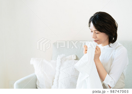 洗ったタオルの匂いを確認する女性 98747003