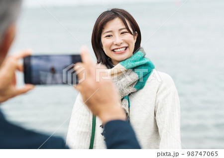 海で写真を撮るカップル 98747065