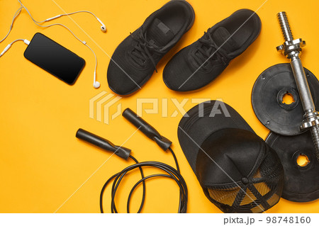 Close-up studio shot of a gym accessories on a yellow background. Top view, flat lay. Close-up studio shot of a gym accessories on a yellow background. Top view, flat lay. 98748160