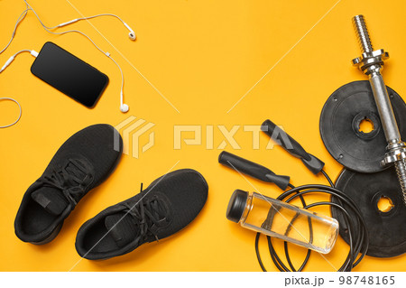 Close-up studio shot of a gym accessories on a yellow background. Top view, flat lay. 98748165