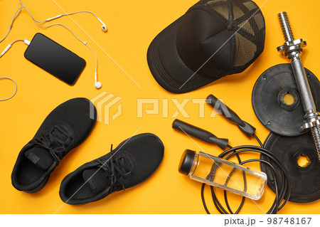 Close-up studio shot of a gym accessories on a yellow background. Top view, flat lay. Close-up studio shot of a gym accessories on a yellow background. Top view, flat lay. 98748167