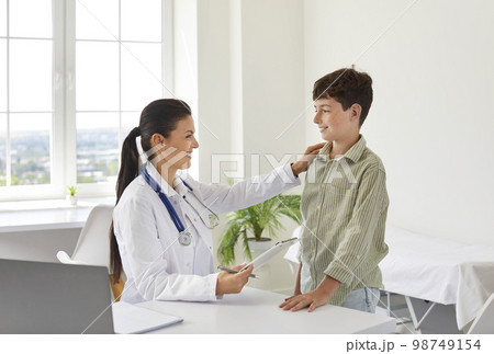 Smiling, friendly doctor examining a preteen child boy on checkup appointment. 98749154