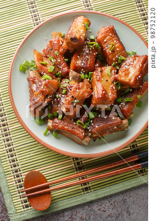 Homemade Chinese pork short ribs in sweet and sour sauce close-up in a plate. Vertical top view Homemade Chinese pork short ribs in sweet and sour sauce close-up in a plate. Vertical top view 98752120