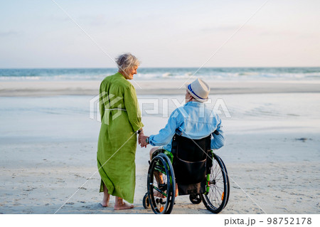 Senior man on wheelchair enjoying together time with his wife at sea. 98752178
