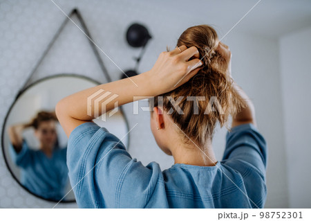 Young woman taking care of her hair, morning beauty routine concept. 98752301