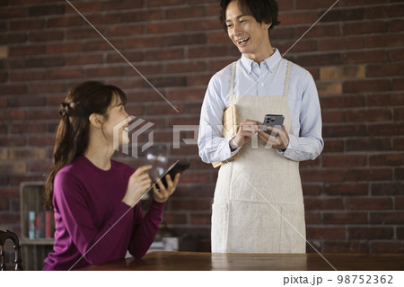 カフェでウェーターと話す若い女性 98752362