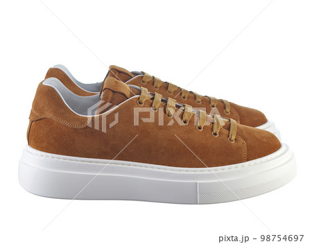 Side view fashionable modern sneakers made of reddish-yellow suede, lace-up, with a massive shock-absorbing sole, isolated on a white background. 98754697