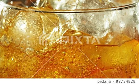 Detail of cider with ice cubes in glass. 98754929