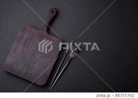 Empty wooden cutting board on dark textured concrete background Empty wooden cutting board on dark textured concrete background 98755702
