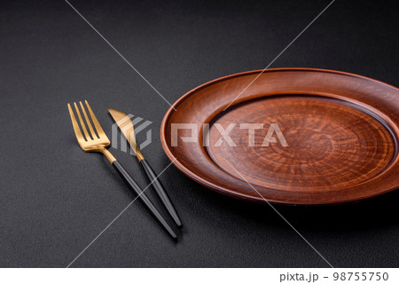 Empty ceramic round plate on dark textured concrete background Empty ceramic round plate on dark textured concrete background 98755750