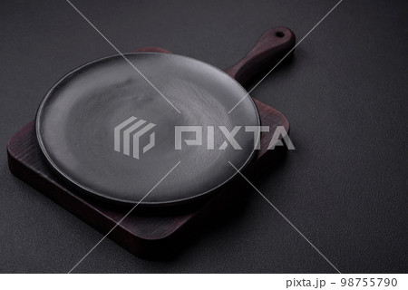 Empty ceramic round plate on dark textured concrete background 98755790