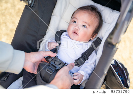 おでかけ先でベビーカーに乗ってパパにシートベルトをつけてもらう赤ちゃん おでかけ先でベビーカーに乗ってパパにシートベルトをつけてもらう赤ちゃん 98755796
