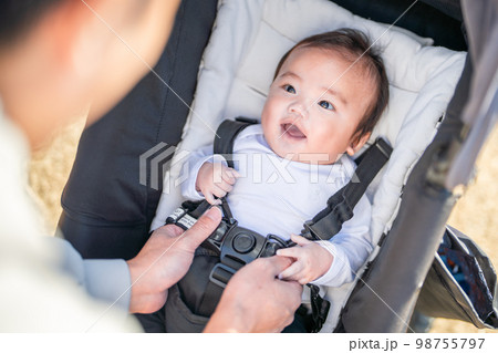 おでかけ先でベビーカーに乗ってパパにシートベルトをつけてもらう赤ちゃん おでかけ先でベビーカーに乗ってパパにシートベルトをつけてもらう赤ちゃん 98755797