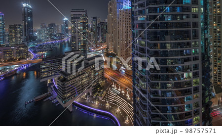 Aerial view to Dubai marina skyscrapers around canal with floating boats night Aerial view to Dubai marina skyscrapers around canal with floating boats night 98757571