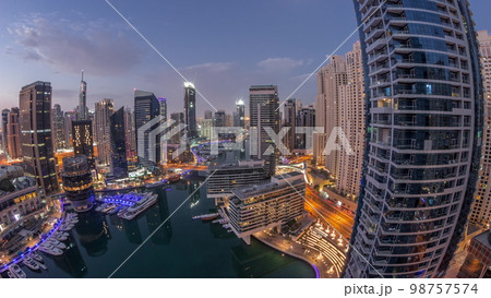 Aerial view to Dubai marina skyscrapers around canal with floating boats night to day 98757574