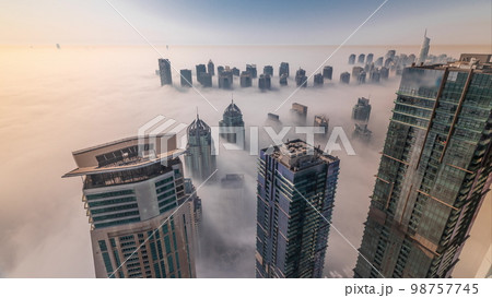 Rare early morning winter fog above the Dubai Marina skyline and skyscrapers rooftops aerial . 98757745