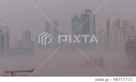 Dubai skyscrapers with morning fog in business bay district night to day . 98757772