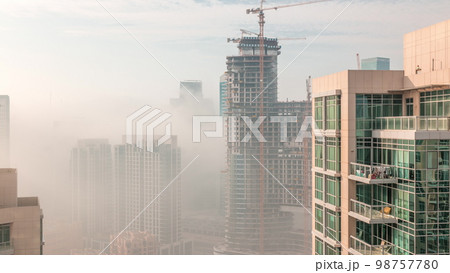 Dubai skyscrapers covered by morning fog in business bay district during sunrise . Dubai skyscrapers covered by morning fog in business bay district during sunrise . 98757780