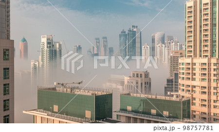 Dubai skyscrapers covered by morning fog in business bay district during sunrise . Dubai skyscrapers covered by morning fog in business bay district during sunrise . 98757781
