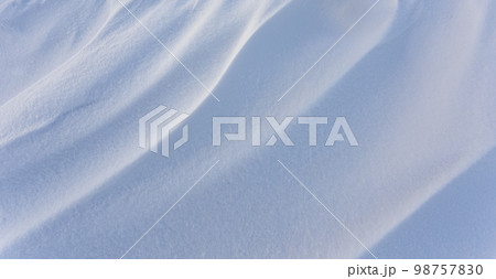 Snowdrift waves in sunset light, winter background of snow waves 98757830