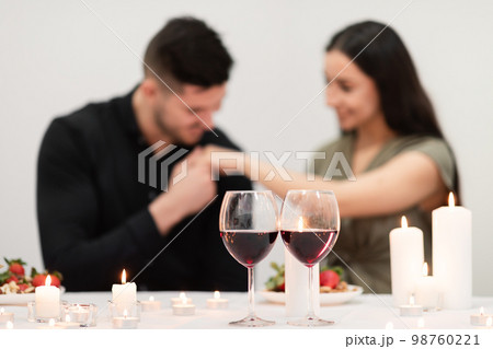 Two glasses with red wine over man kissing woman hand 98760221