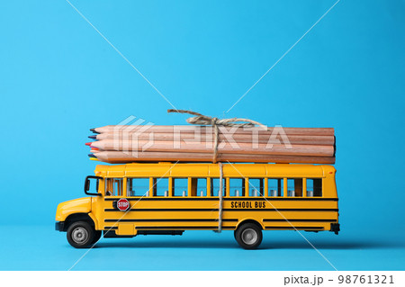 School bus model with color pencils on light blue background. Transport for students School bus model with color pencils on light blue background. Transport for students 98761321